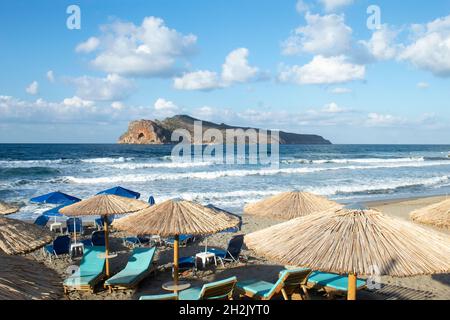 Kreta Insel Griechenland schönes kleines Resort von Agia Marina, in der Nähe von Chania Stadt Liegestühle und Sonnenschirme am Strand Blick auf Theodori Insel Landschaft A Stockfoto