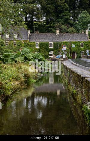 Die Steinbrücke über den Fluss Coln und das efeubedeckte Swan Hotel im malerischen Dorf Bibury in Gloucestershire Cotswolds, England. Stockfoto