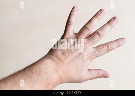 Draufsicht des männlichen Handrückens mit ausgebreiteten fünf Fingern aus der Nähe über hellbraunem Holzbrett Stockfoto