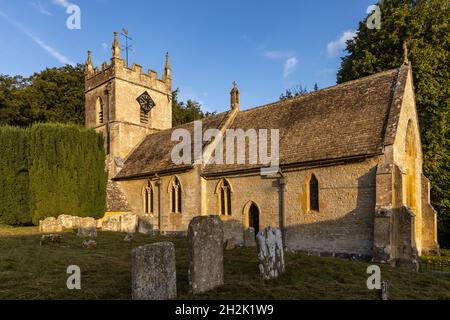 Die Morgensonne erleuchtet die wunderschöne St. Peter's Kirche im malerischen Cotswold Dorf Upper Slaughter in Gloucestershire, England. Stockfoto