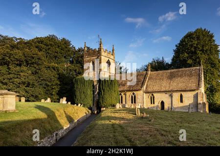 Die Morgensonne erleuchtet die wunderschöne St. Peter's Kirche im malerischen Cotswold Dorf Upper Slaughter in Gloucestershire, England. Stockfoto