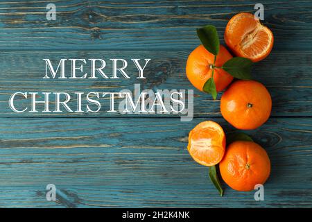 Mandarinen und Text Frohe Weihnachten auf Holzhintergrund Stockfoto