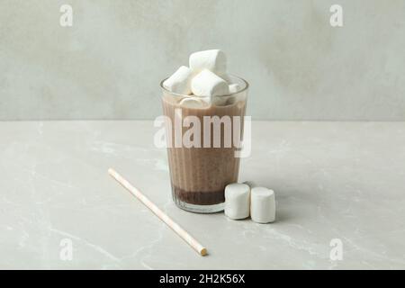 Kakao mit Marshmallows im Glas auf einem hellen Tisch. Süßer heißer Kakao mit Marshmallows in einem klaren Glas, gemütliches Dessertgetränk Stockfoto