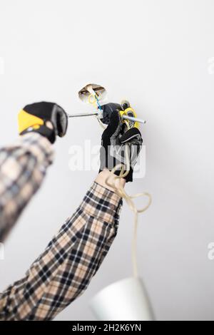 Elektriker repariert die elektrische Verkabelung der Deckenleuchte zu Hause Stockfoto