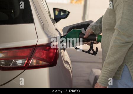 Aufnahme einer hispanischen Frau, die in Spanien ein Auto mit einer grünen Düse betankt Stockfoto