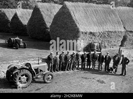 Landarbeiter mit Traktoren und aufgeschlagen Heuhaufen Großbritannien der 1950er Jahre Stockfoto