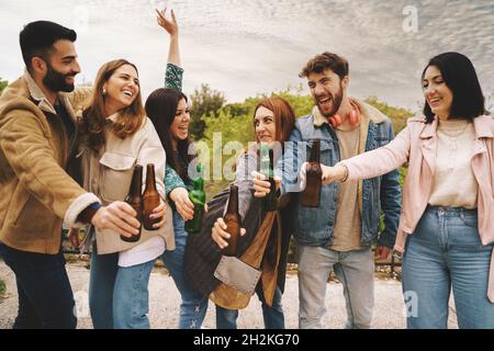 Fröhliche Menschen tanzen im Park und trinken gemeinsam Bier Stockfoto