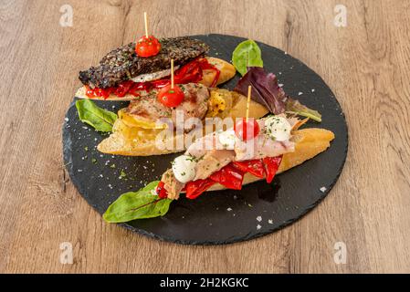 Tablett mit verschiedenen spanischen Pinchos mit schwarzem Pudding aus Reis, gerösteten roten Paprika, Ziegenkäse, Schweinefleisch und gebratene Kartoffel mit Zwiebel, Thunfischbauch, Rahm c Stockfoto