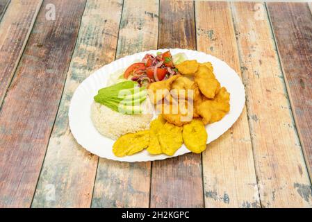 Ecuadorianisches Rezept von panierten Garnelen mit Stücken gebratener reifer Banane, Tomatensalat und violetter Cebola, gekochtem weißem Reis und reifer Avocado Stockfoto