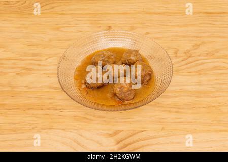 Spanisches Rezept für Fleischbällchen mit Sauce auf einer transparenten Glasplatte Stockfoto