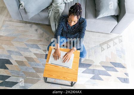 Schöne junge schwarze Frau hat einen Zoom-Anruf oder arbeitet in von Laptop online Stockfoto