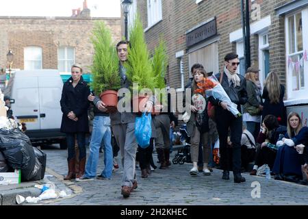 London, Großbritannien - am 20. November 2019 Kaufte Eine Gruppe von Freunden auf dem Columbia Road Flower Market eingetopften Thuja und tragen ihn nach Hause. Stockfoto