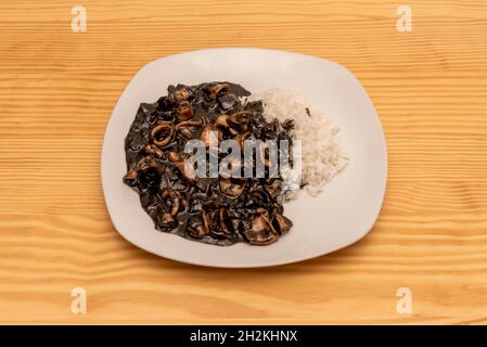 Typisches Rezept aus dem Norden Spaniens mit Tintenfisch mit Tintensauce und weißem Reis garniert Stockfoto