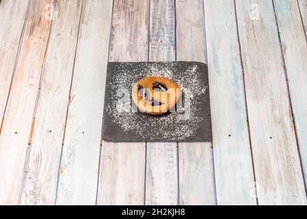 Frisch gebackene Plätzchen mit Schokoladenstückchen mit Puderzucker auf schwarzem Schieferteller Stockfoto