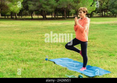Ältere Frau macht Yoga-Workout-Routine im Freien im Stadtpark - ältere und gesunde Lebensweise Konzept Stockfoto