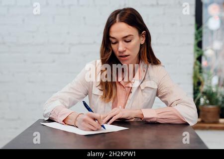 Porträt einer Ärztin, die an ihrem Schreibtisch schreibt. Stockfoto