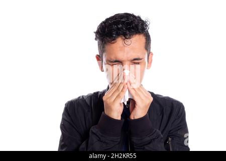 Mann bläst mit beiden Händen in die Nase. Weißer Hintergrund. Junger erwachsener Mann mit Erkältung mit weißem Taschentuch. Stockfoto