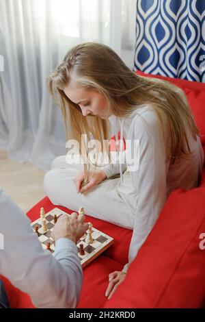 Junges Paar, das zu Hause im Wohnzimmer Schach spielt Stockfoto