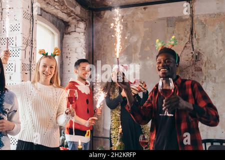 Eine Gruppe von Freunden, die bei der Weihnachtsfeier mit Getränken anstoßen. Stockfoto