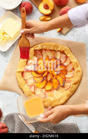 Frau Vorbereitung pfirsich Galette am Tisch Stockfoto