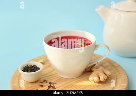 Holzbrett mit einer Tasse leckeren Preiselbeertee auf farbigem Hintergrund, Nahaufnahme Stockfoto