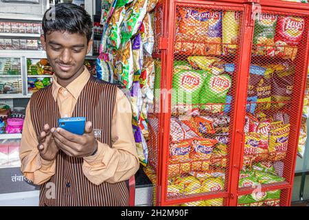 Mumbai Indien, Apollo Bandar Strand Road, Manager Convenience Store, Smartphone Handy SMS suchen Nachrichten, Junk-Food-Snack Lay's Kartoffelchips Stockfoto