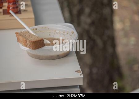 Ein Teller mit Suppe und einem Löffelnahrung für die Obdachlosen, die Flüchtlinge füttern. Stockfoto