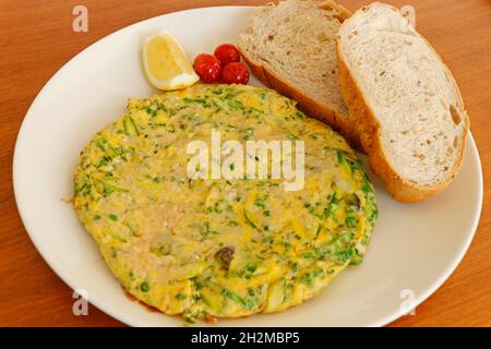 Bio-Eieromelett gefüllt mit Käse, Spargel, Spinat, Grünkohl mit Tomaten und Brotscheiben serviert, Frühstück Konzept Lebensmittel Stockfoto