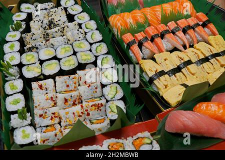 Eine große Auswahl an japanischen Sushi-Brötchen in einem Boot, inklusive Lachs, Thunfisch, Krabben, Garnelen usw. Stockfoto