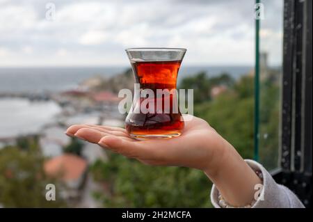 Teetasse Armudas auf Frauenhand, traditioneller türkischer Tee türkischer roter aromatischer Tee in traditioneller authentischer Glastasse - armudu Stockfoto