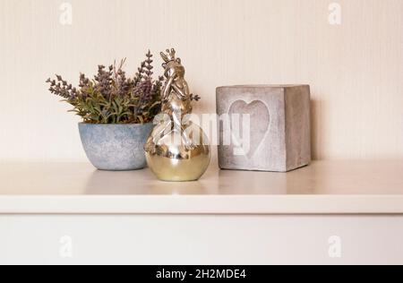 Stillleben aus einer Vase mit Lavendel, einer Froschfigur mit einer Kerze auf einem weißen Tisch. Stockfoto