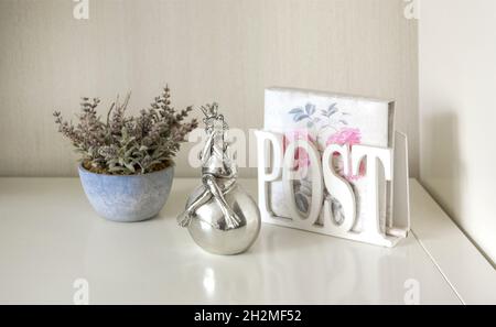 Lila Lavendel blüht in einem blauen Blumentopf, Froschfigur und Serviettenhalter auf einem weißen Tisch. Stockfoto