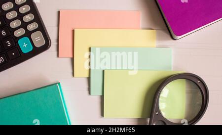 Farbige Aufkleber, Taschenrechner und farbige Notizbücher auf weißem Hintergrund Stockfoto