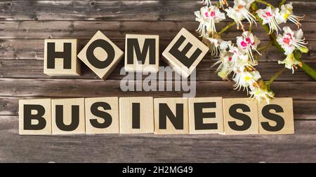 Home Business Text im Vintage-Stil auf Blöcken, Blumen auf Holzhintergrund Stockfoto