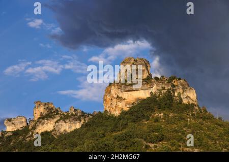 Felsen der Tarn-Schlucht (Rocher de Capluc), die kurz vor Sonnenuntergang orange glühen und dunkle Wolken bei Le Rozier, Ockitanie, Frankreich Stockfoto