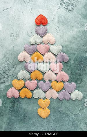 Weihnachtsbäume aus bunten Samt-Herzen auf einem grünen strukturierten Hintergrund. Flach liegend. Valentinstag, Neujahr. Das Konzept der Ökologie, Wald Stockfoto