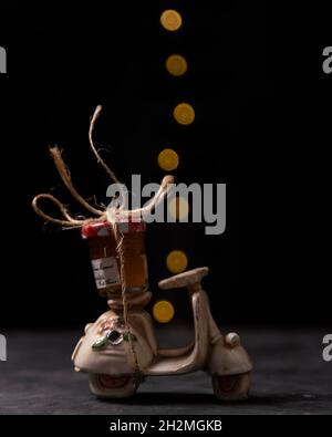 Ein kleines Glas mit Pfirsichmarmelade wird mit Garn an einen Modellroller mit Bokeh-Lichtern im Hintergrund gebunden Stockfoto