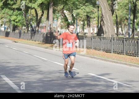 DNIPRO, UKRAINE - 26. SEPTEMBER 2021: Einsamer glücklicher Mann, der auf einer leeren Stadtstraße während der 21 km langen Strecke des Almaz-Gruppe-Dnipro-Marathons läuft Stockfoto