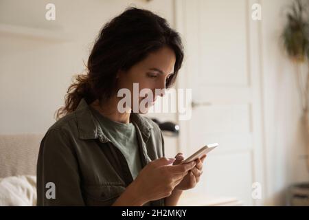 Fokussierte positive Handy-Nutzer SMS-Nachricht, mit App auf dem Smartphone Stockfoto