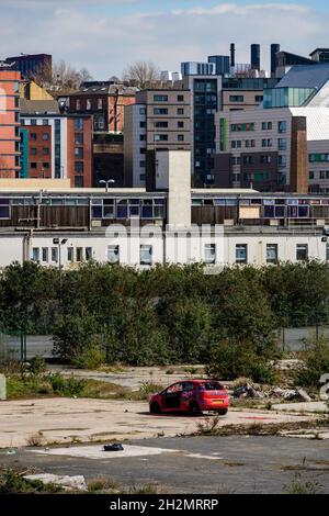 Erschlossenes Land (Entwicklung von Studentenwohnungen) und verfallendes Abfallgebiet (verlassene Vandalismusfahrzeuge, Brachland) - Leeds, Yorkshire, England Großbritannien Stockfoto
