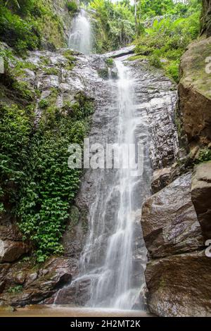 Vertikale Aufnahme eines wunderschönen Wasserfalls, der an einem sonnigen Tag die Felsen hinunter fließt Stockfoto