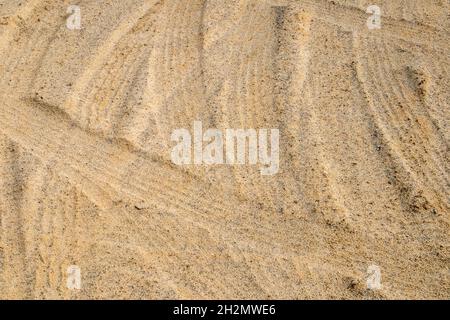 Leichter Sand, der von Reifenspuren zertrampelt wird, kann als Hintergrund oder Textur verwendet werden Stockfoto
