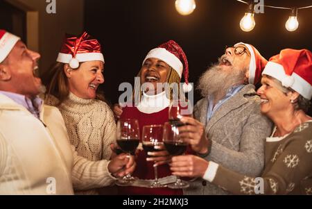 Glückliche ältere Freunde feiern Weihnachtsferien beim Toasten mit rot Weingläser auf der Terrasse des Hauses Stockfoto