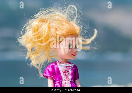 Kinderpuppe aus Kunststoff, in einem rosa Kleid gekleidet. Stockfoto