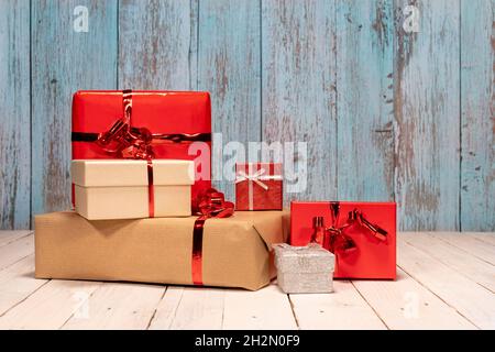 Komposition mit vielen Geschenken und Platz für Ihre Herzliche Glückwünsche. Rote, braune und silberne Geschenkschachteln auf einem weißen Holztisch für ein Weihnachtsfest voller Stockfoto