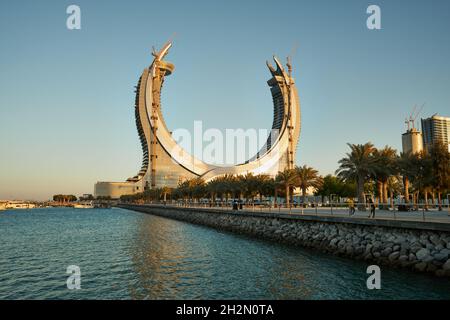 Lusail Corniche am Yachthafen in Lusail City, Katar, Sonnenuntergangsaufnahme mit Menschen, die auf der Promenade mit Skyline im Hintergrund spazieren gehen Stockfoto