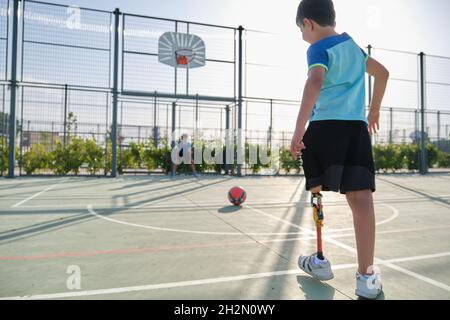 Zwei Freunde spielen Fußball, einer hat eine Beinprothese und tritt eine Strafe. Stockfoto