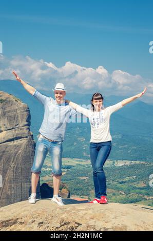 Junge Männer und Frauen übernachten, kuscheln, lächeln und betrachten die Kamera auf Meteora Steinfelsen und Bergen, Tal und blauem Himmel im sonnigen Sommer da Stockfoto