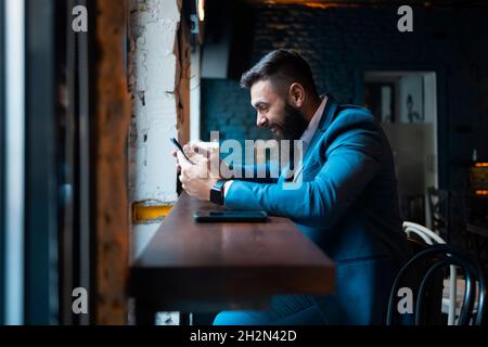 Ein Mann in einem Anzug, der in einer Bar lacht Stockfoto