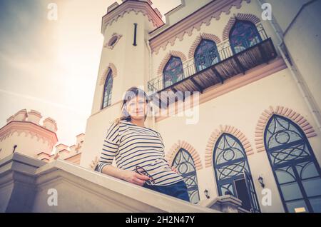 Junge schöne Mädchen Reisende posiert in der Nähe von Schloss Schloss Gebäude in Kosava Kossovo in sonnigen Sommertag, blauer Himmel Hintergrund, Urlaub in Brest Region, Stockfoto